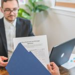Corretor e cliente analisam uma solicitação de empréstimo e documentos sobre a mesa.