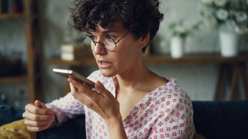 Mulher usa um comando de voz no smartphone em casa.