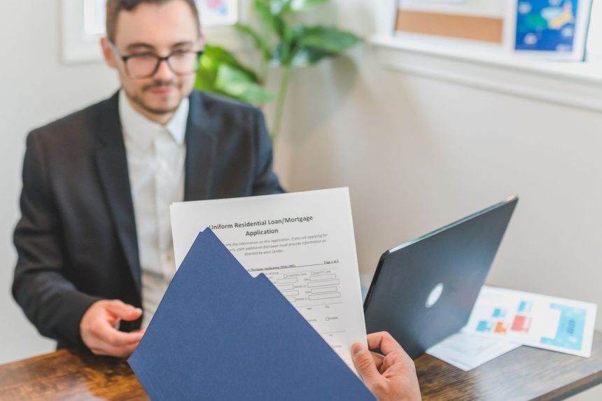 Corretor e cliente analisam uma solicitação de empréstimo e documentos sobre a mesa.