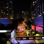Vista noturna de Brickell, em Miami, com arranha-céus iluminados, trânsito e movimento urbano.