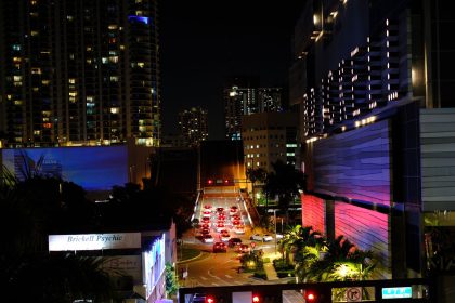 Vista noturna de Brickell, em Miami, com arranha-céus iluminados, trânsito e movimento urbano.