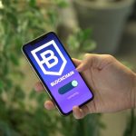 Mão segurando um smartphone com a tela de um aplicativo de blockchain.