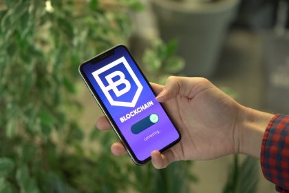 Mão segurando um smartphone com a tela de um aplicativo de blockchain.